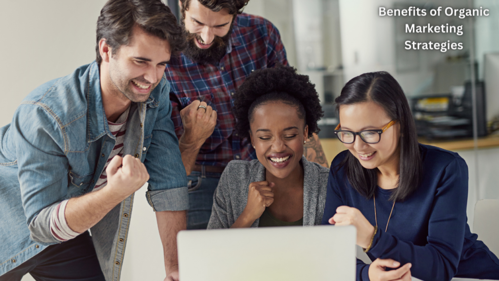 Two men and two women analyzing the Benefits of Organic Marketing Strategies on a laptop and smiling