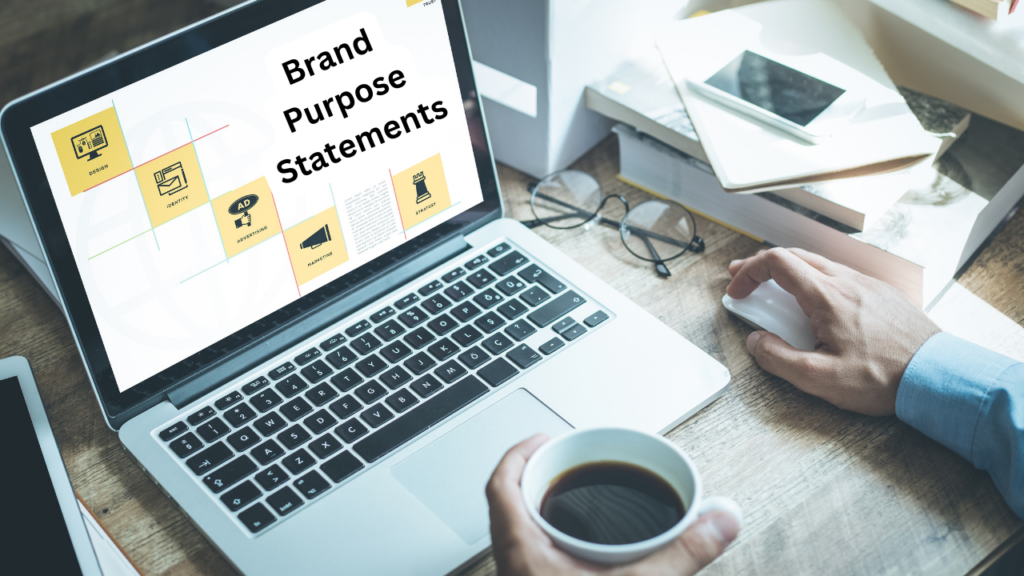 Man having a cup of coffee in hand and glasses, mobile and books on table checking on laptop Brand Purpose Statements